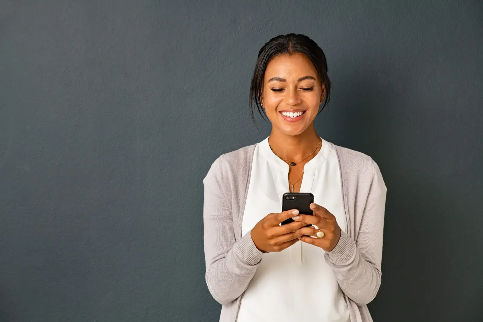 Mujer sonriendo mientras usa su celular